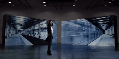 woman standing in a room with projected scenes on the walls behind her